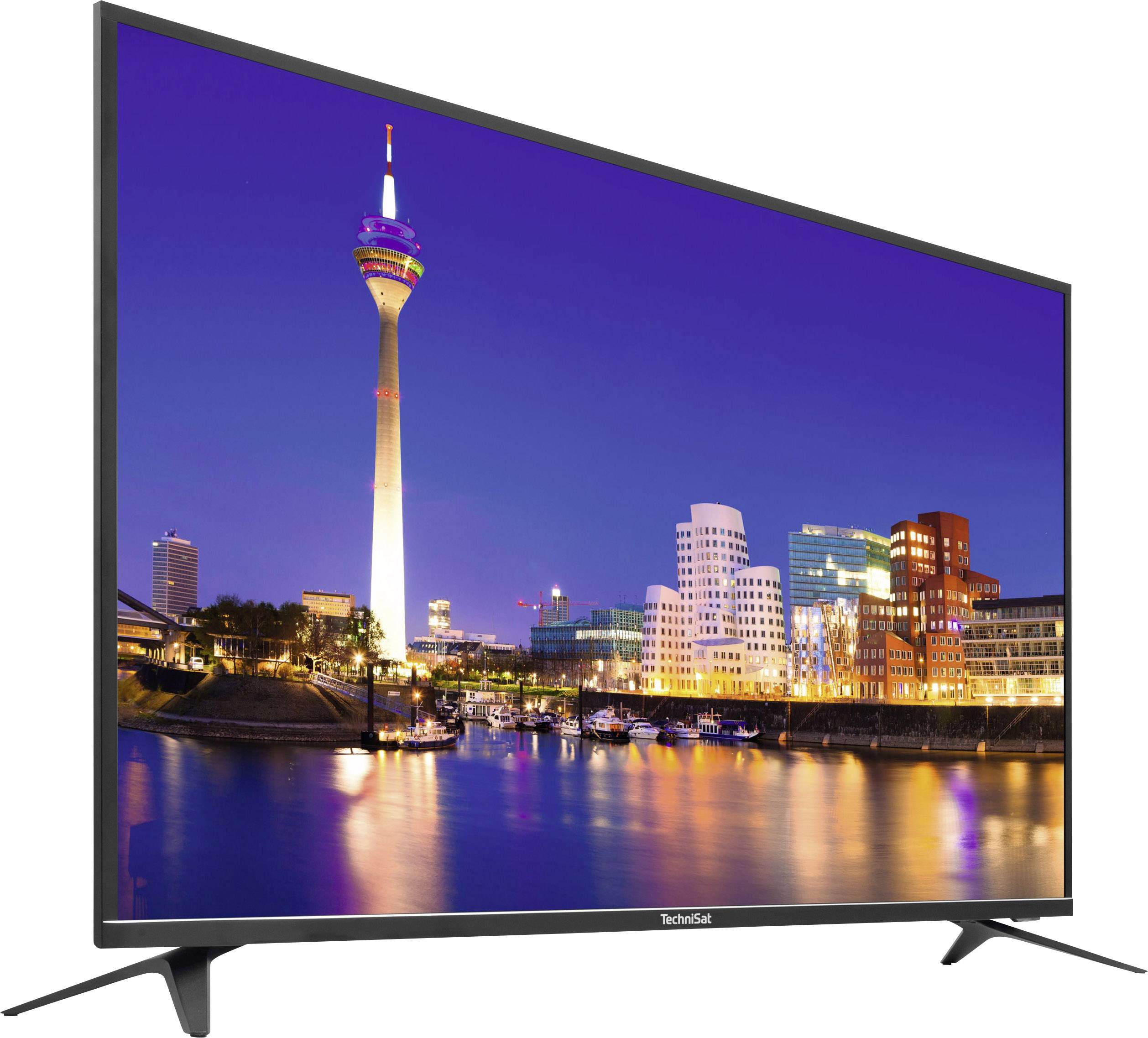 Płaski telewizor wyświetla nocną panoramę miasta z podświetloną wieżą telewizyjną oraz nowoczesnymi budynkami odbijającymi się w wodzie.