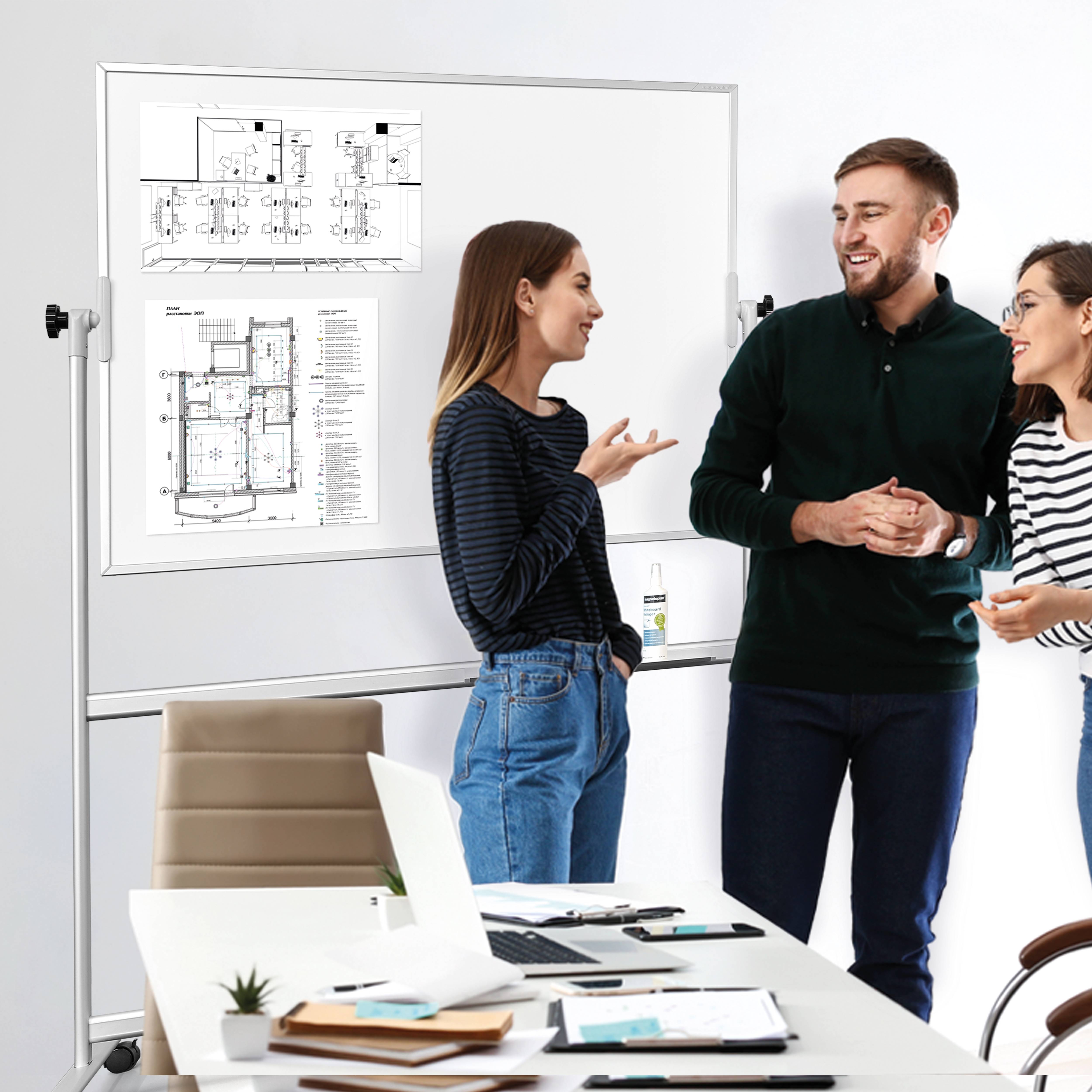 Trzej współpracownicy dyskutują o architektonicznych planach pięter przypiętych na tablicy w sali konferencyjnej.