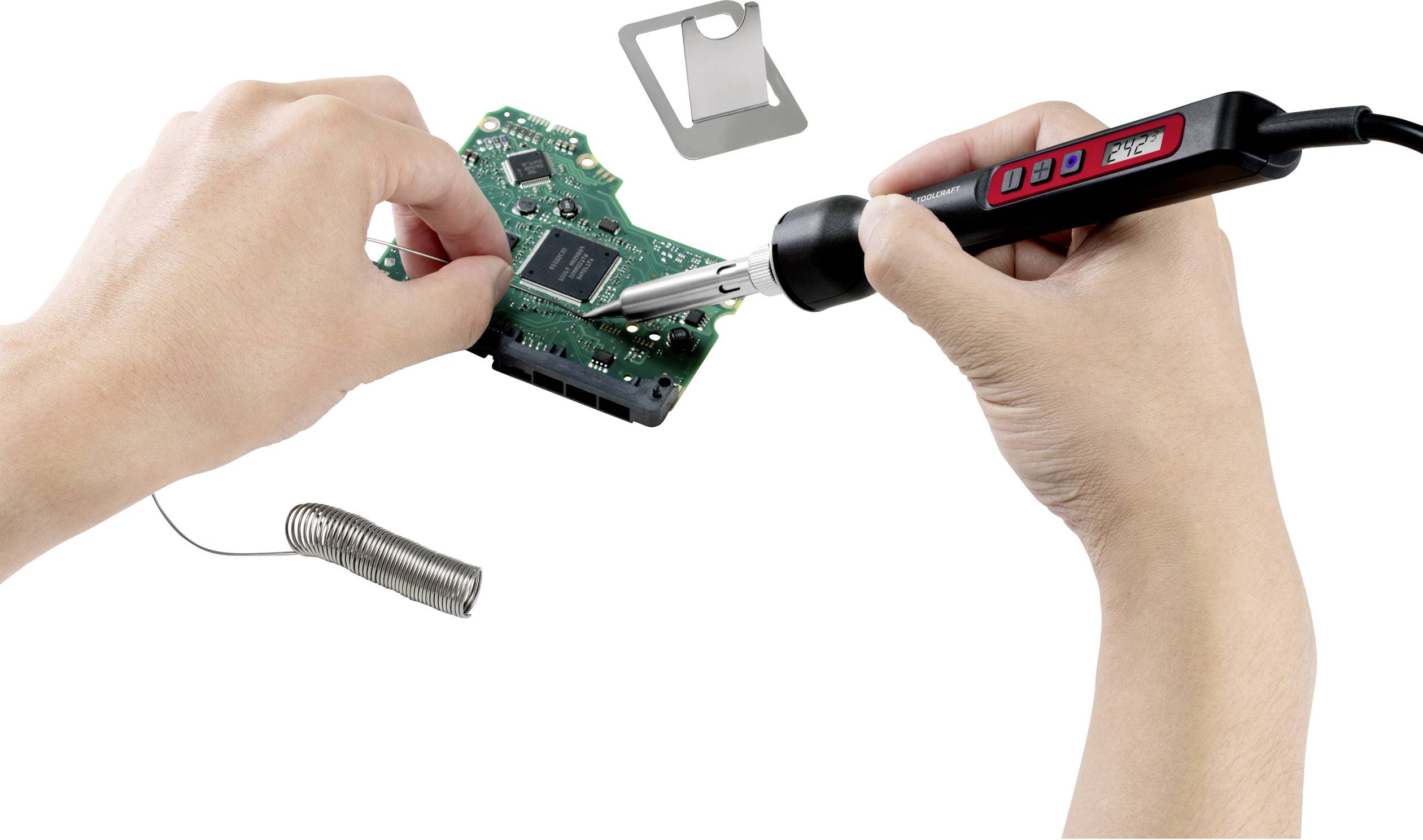 Jedna ręka lutuje za pomocą lutownicy na zielonej płytce drukowanej, podczas gdy druga ręka trzyma płytkę. W tle leży cyna lutownicza.