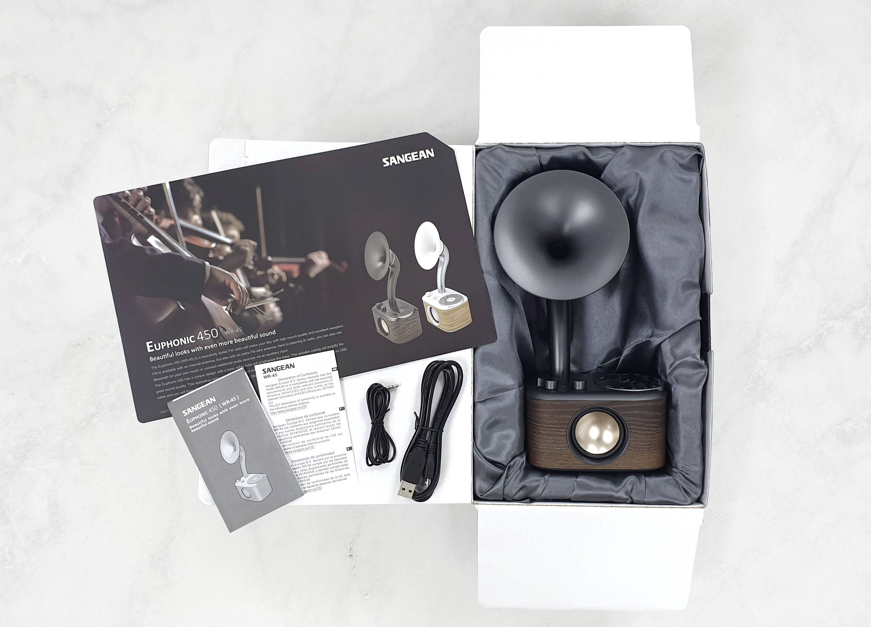Otwarty karton z retro głośnikiem, kablem USB, kablem audio oraz broszurami. Widoczny tekst marki 'SANGEAN'.