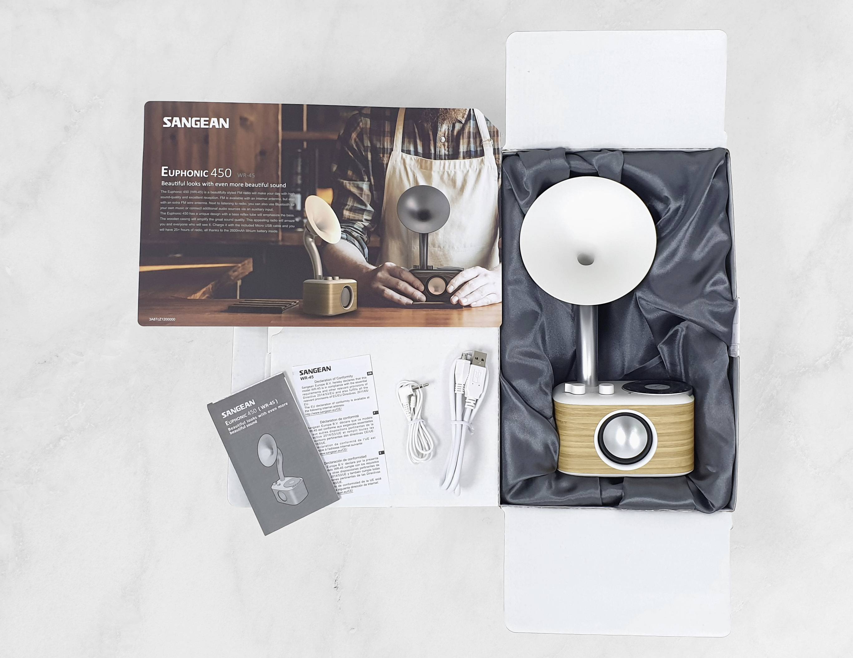 Retro radio w pudełku z instrukcją obsługi, kablami i informacjami o produkcie na stole.