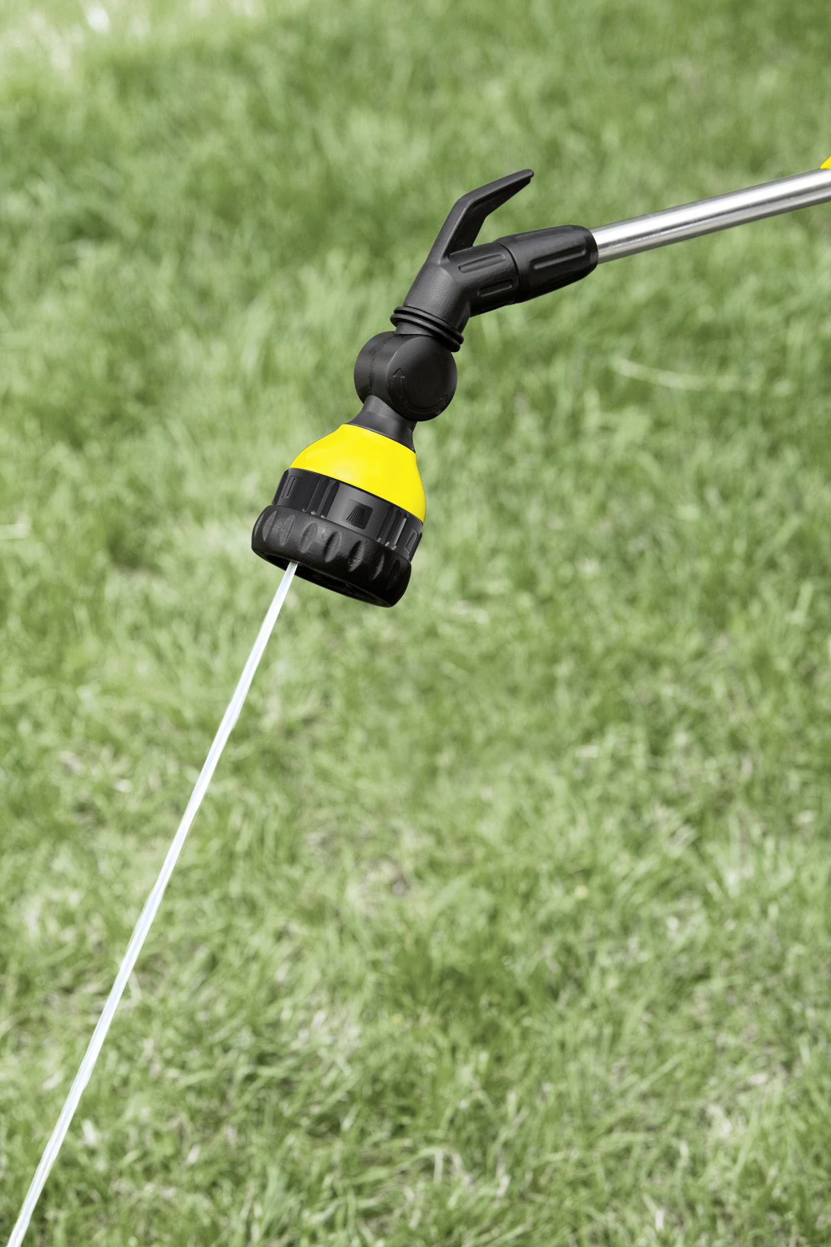 Żółta końcówka węża ogrodowego rozpyla wodę na zielonej powierzchni trawnika.