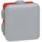 Szara, kwadratowa, elektryczna puszka rozgałęźna marki Legrand, z czerwonym tłem i przelotkami kablowymi, stopień ochrony IP55.