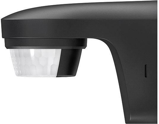 Czarny czujnik ruchu w prostokątnej obudowie z białą kopułką, widok z boku. Stosowany do wykrywania ruchu na zewnątrz.