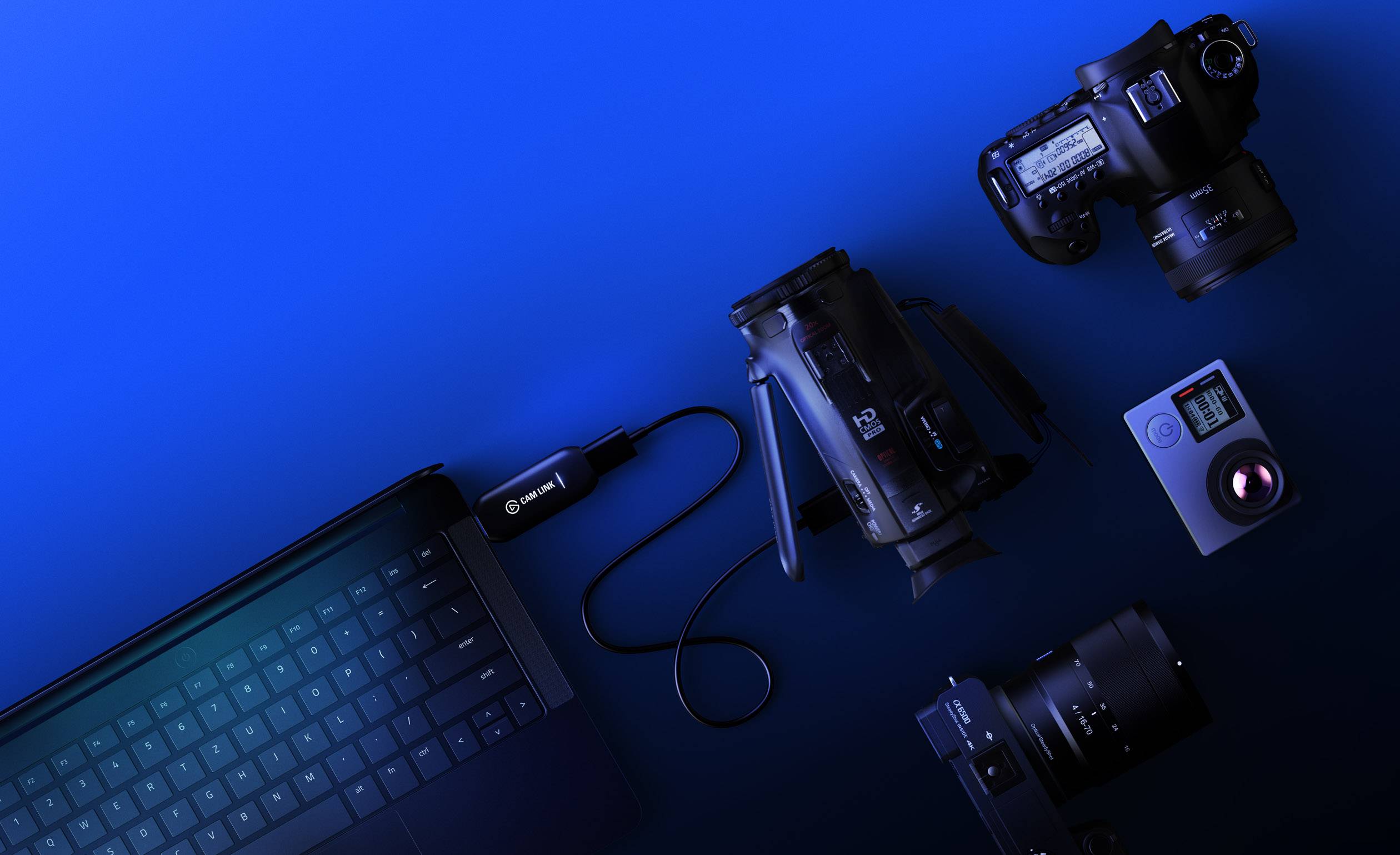 Laptop i różne kamery są połączone kablem, ułożone na niebieskim tle. Koncepcja technologiczna.