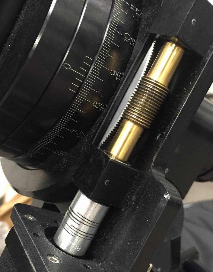 Zbliżenie mechanicznego urządzenia pokazujące koła zębate i skale, prawdopodobnie służące do precyzyjnego pomiaru lub regulacji.