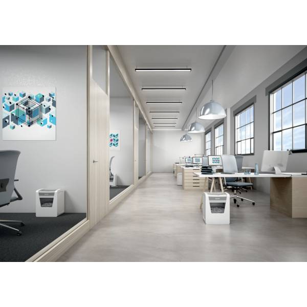 Nowoczesne środowisko biurowe z wieloma biurkami, komputerami i wiszącymi lampami. Na ścianach wiszą abstrakcyjne dzieła sztuki.