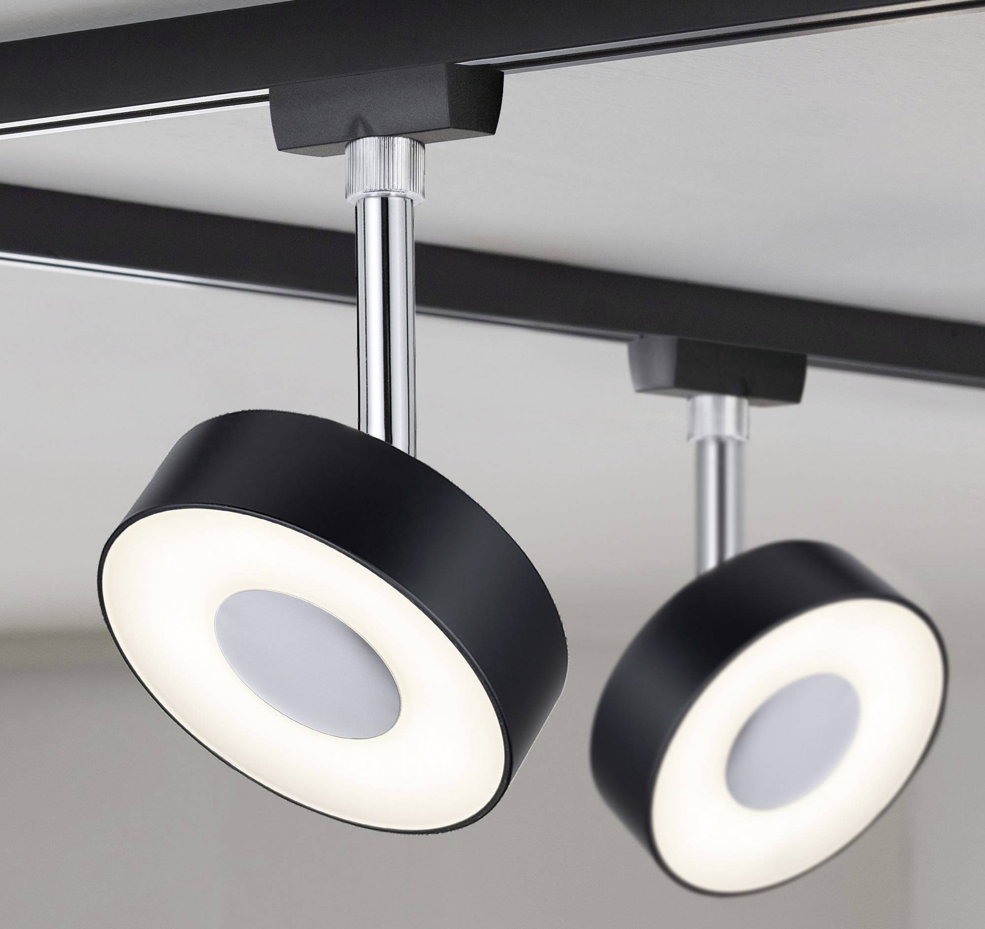 Dwie nowoczesne czarne lampy sufitowe z okrągłym, świecącym brzegiem wiszą pod sufitem i wytwarzają ciepłe, białe światło.