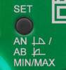 Zbliżenie zielonego panelu sterowania z czarnym przyciskiem oznaczonym napisem 'SET' oraz opcjami 'AN/AB' i 'MIN/MAX'.