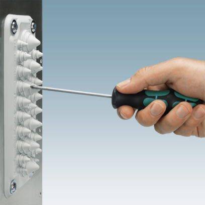 Jedna ręka trzyma wkrętak, który jest wkręcany w śrubę przy urządzeniu z białymi kołkami rozporowymi.