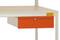 Biurko z pomarańczowym modułem szufladowym pod blatem.