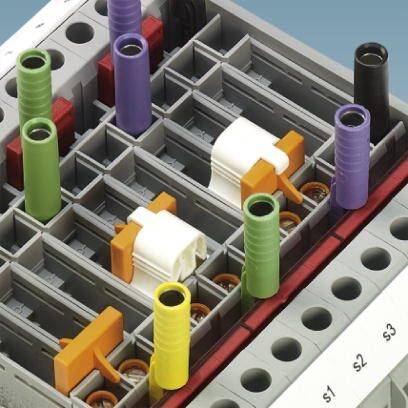 Mechanizm z wielokolorowymi wtyczkami i kablami na szarej strukturze bazowej, prawdopodobnie będący częścią złożonego systemu technicznego.