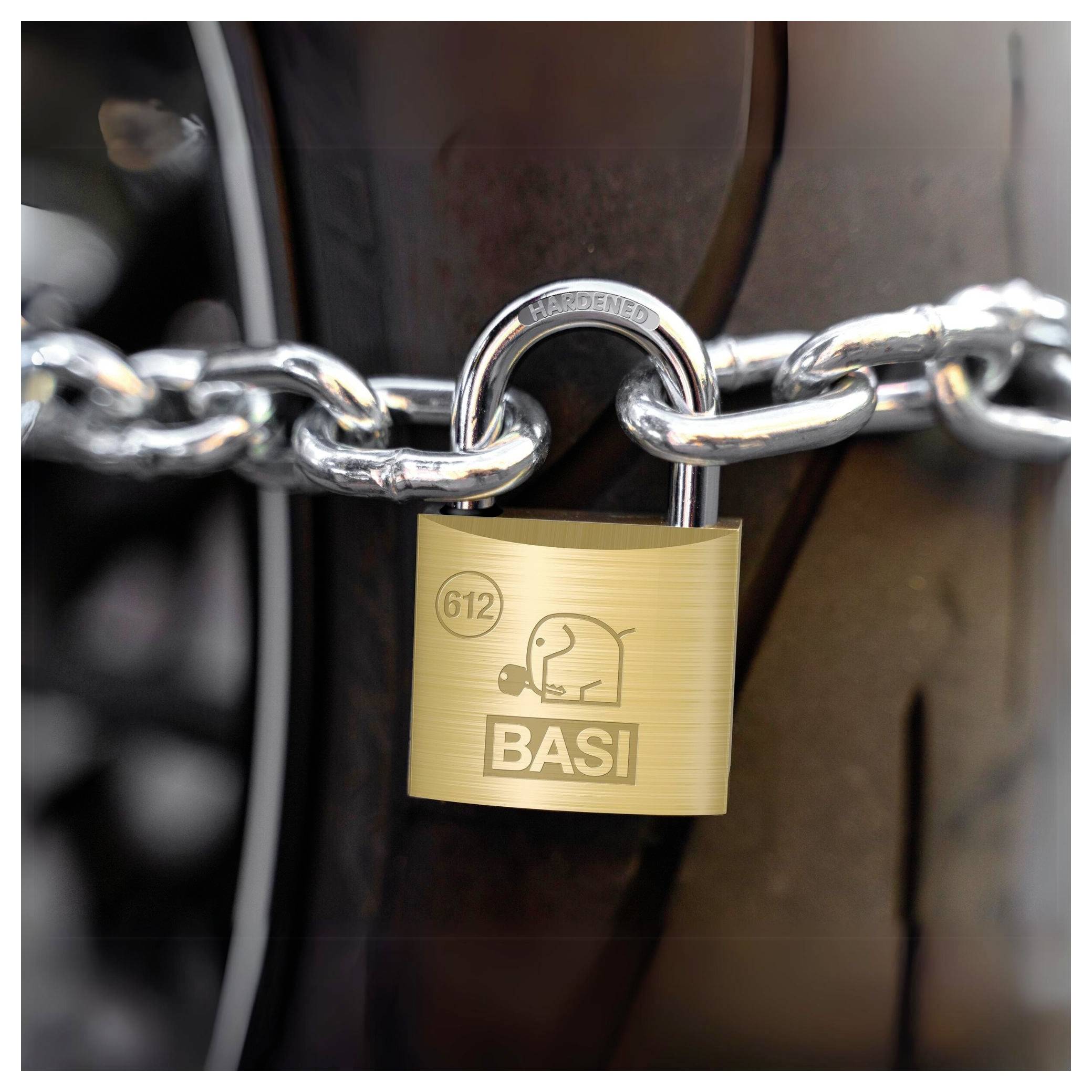 Kłódka marki BASI zabezpiecza grubym łańcuchem stalowym duży opona pojazdu.