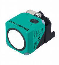 Kwadratowy, zielony czujnik z okrągłym białym elementem i złączem na górnej powierzchni.