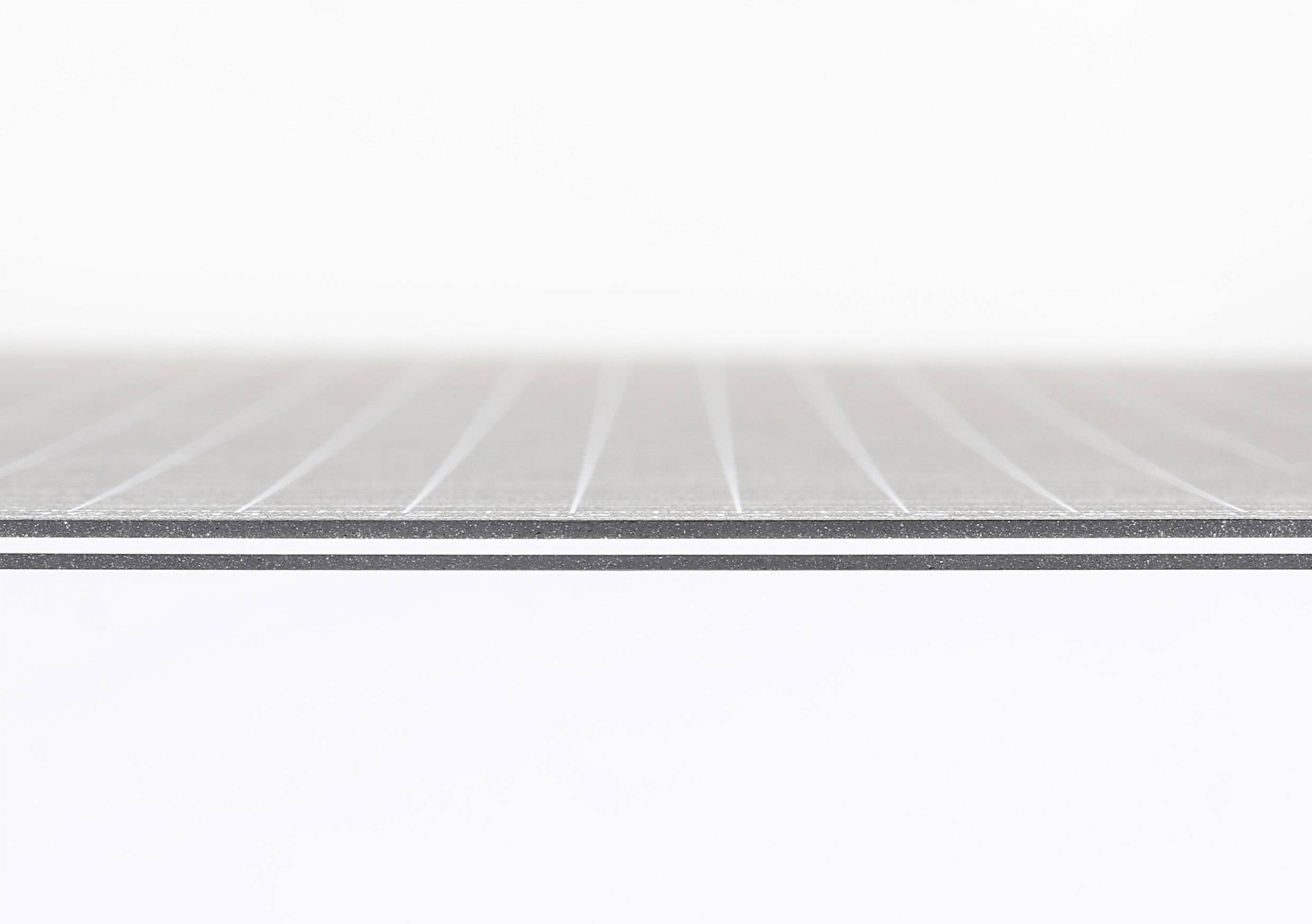 Zbliżenie teksturowanej, szarej powierzchni materiału, prawdopodobnie metalowej płyty z delikatnymi liniami. Jasne tło.