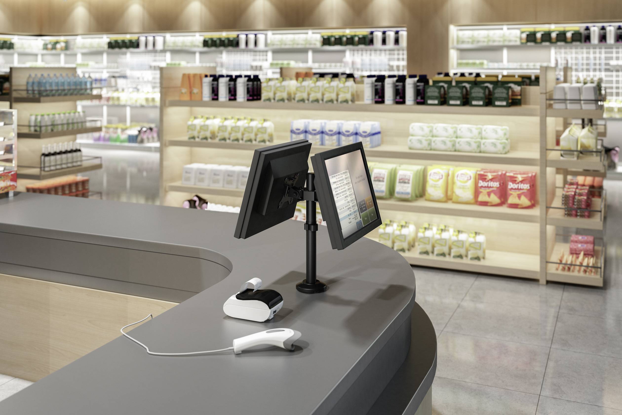 Kasa w supermarkecie z dwoma ekranami i skanerem na ladzie, w tle półki z żywnością i produktami.