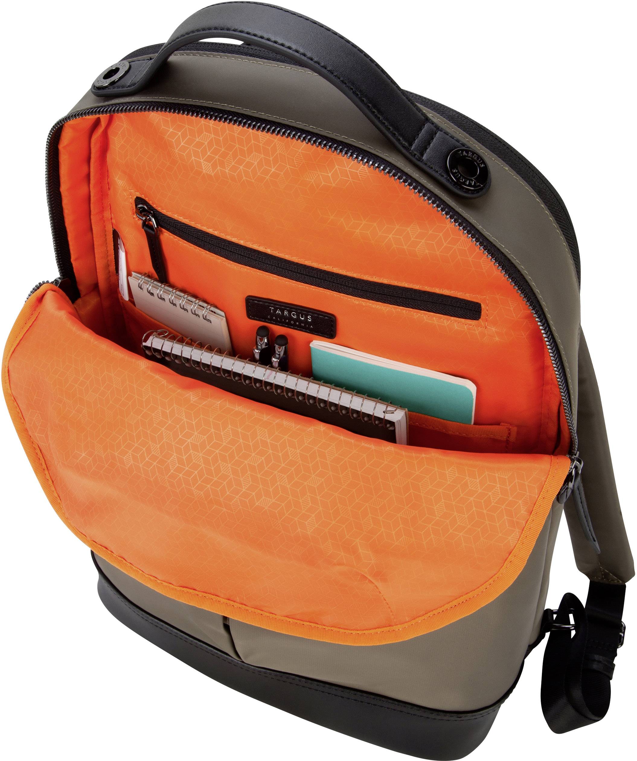 Otwarty plecak z jaskrawo pomarańczową podszewką ujawnia kilka zeszytów i torebek w środku.