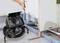 Dłoń trzyma kamerę inspekcyjną skierowaną na rury w podłodze. Monitor wyświetla obraz z kamery, umożliwiając sprawdzenie stanu przewodów.