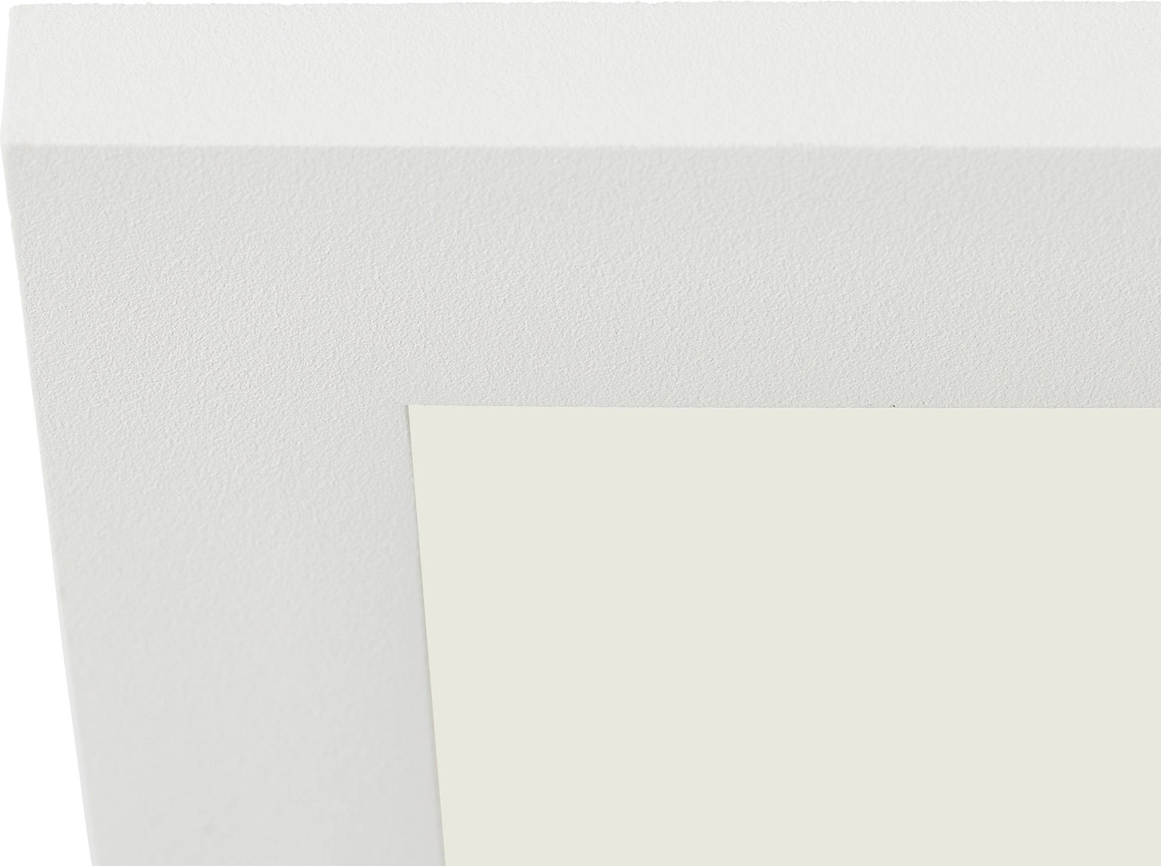 Róg białej ramki na zdjęciu, sfotografowany z góry na neutralnym tle.