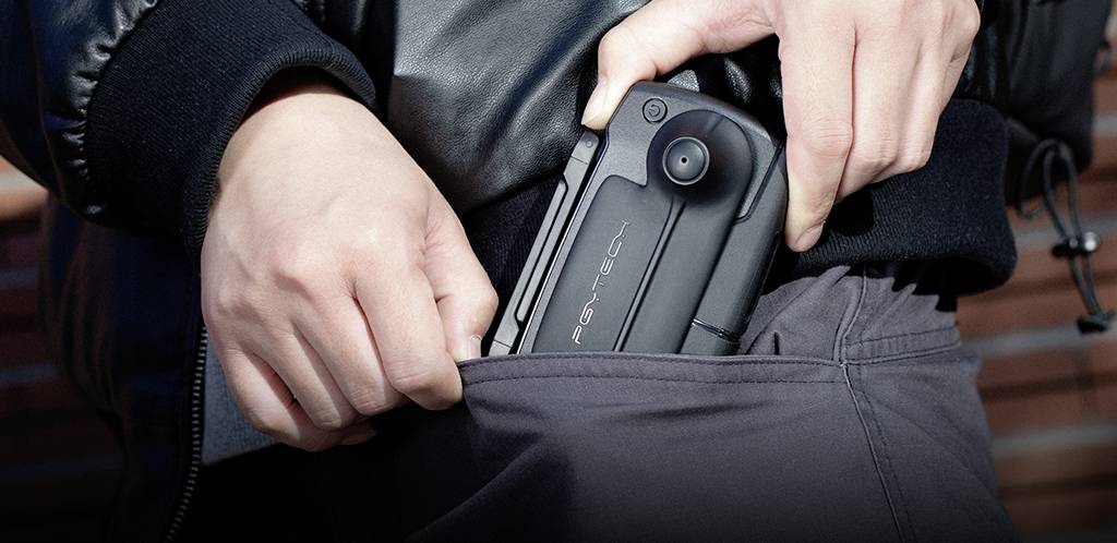 Osoba wkłada przenośną kamerę z napisem 'PSY-TECH' do kieszeni kurtki.