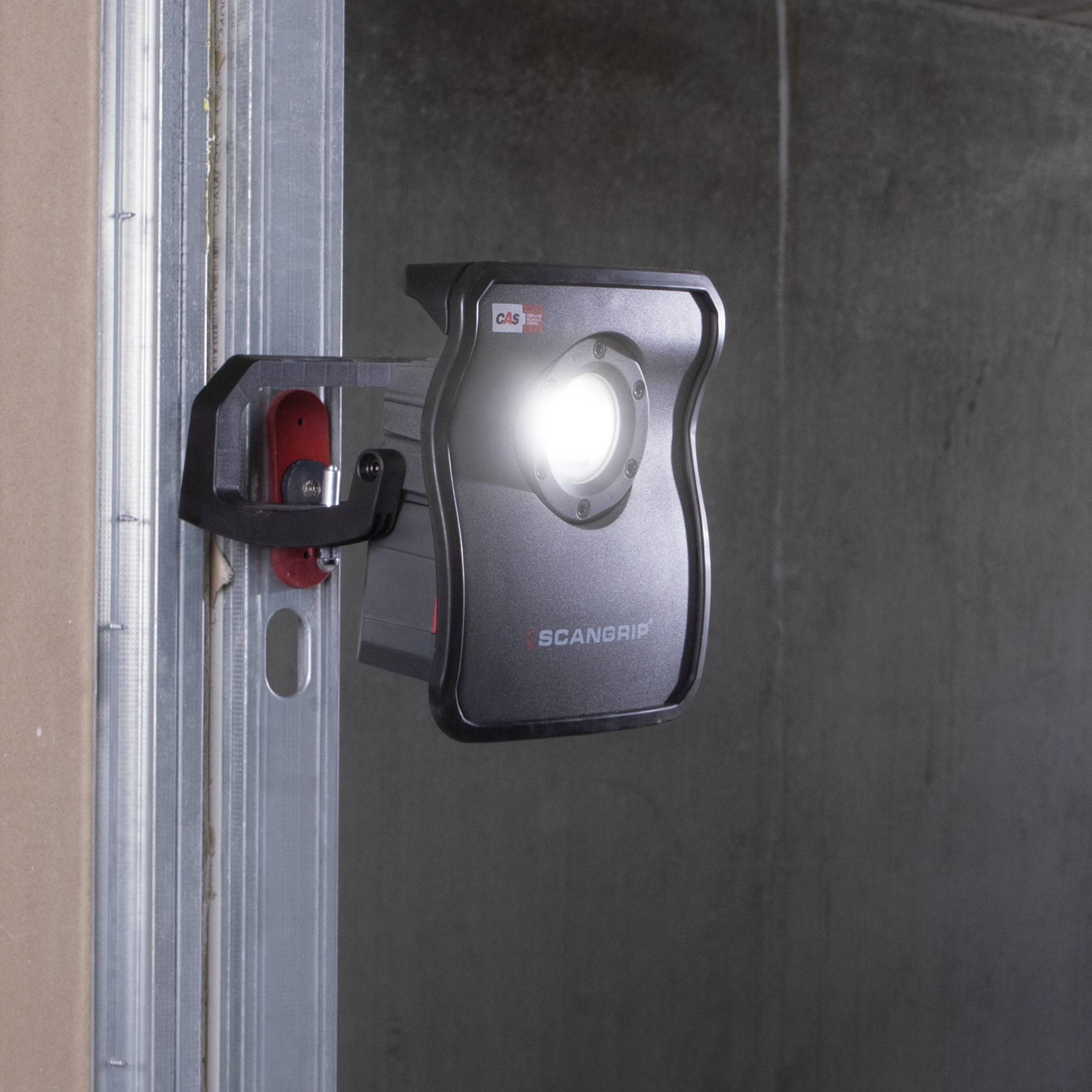 Prostokątna lampa robocza z jasnym reflektorem jest zamocowana na metalowej szynie w przeciwnym razie ciemnym pomieszczeniu.