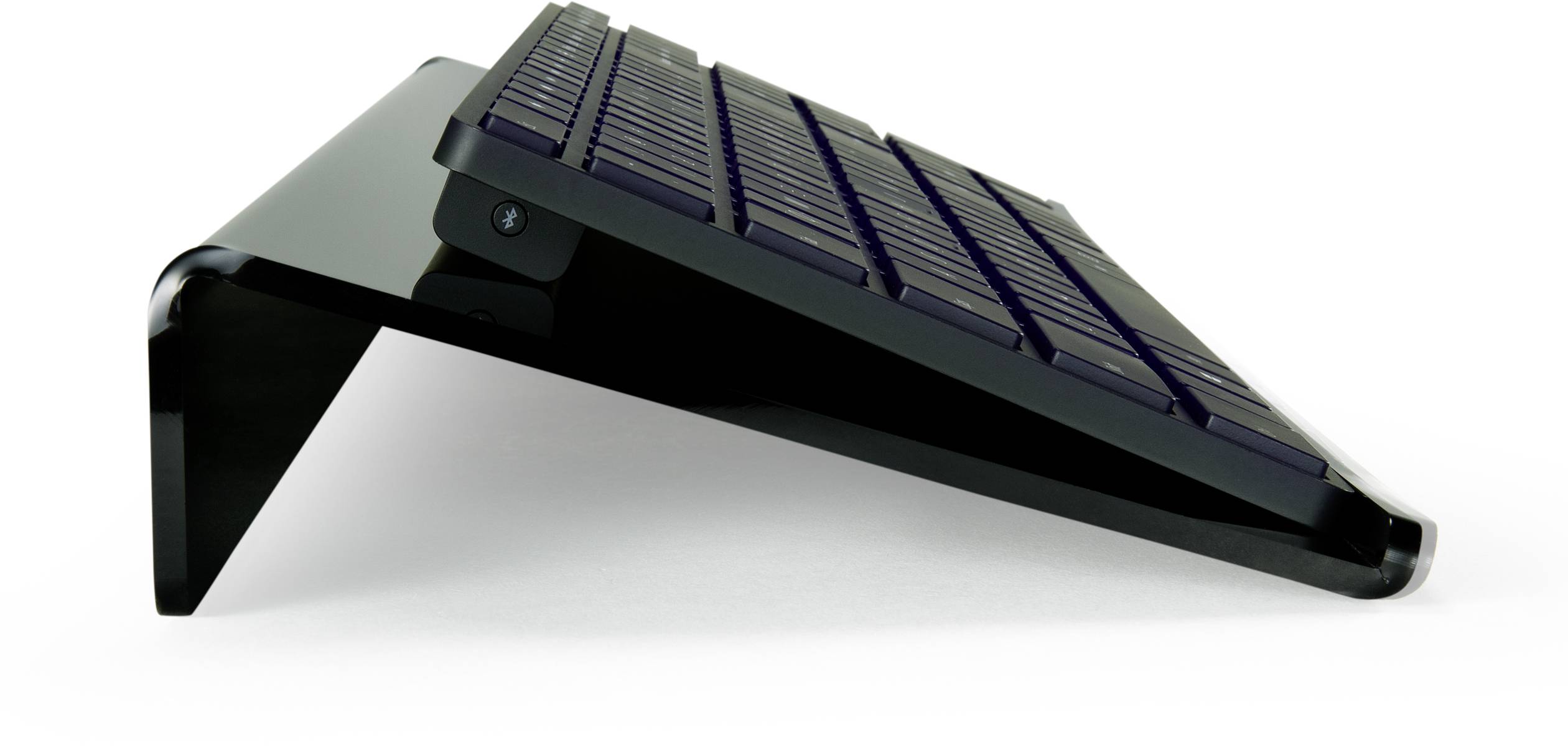 Czarny, ukośny stojak na laptopa z tworzywa sztucznego, pokazujący stronę z zakrzywieniem w kształcie litery J. Zaprojektowany do podniesienia laptopa.