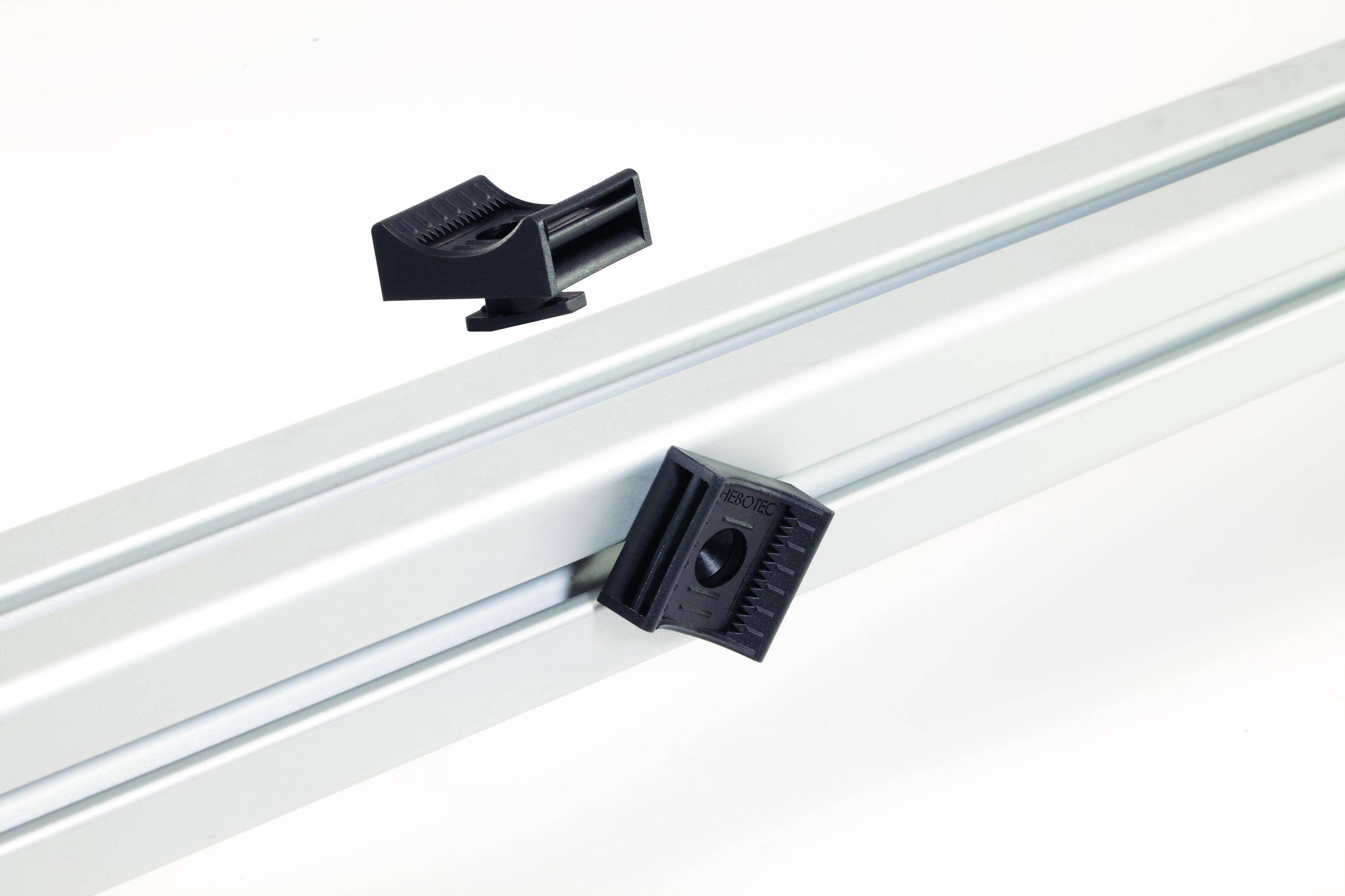 Profil aluminiowy z dwoma czarnymi elementami mocującymi w układzie diagonalnym, na białym tle.