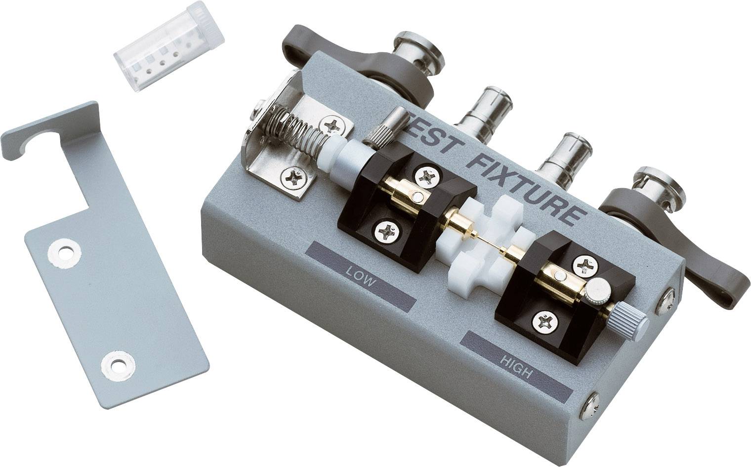 Urządzenie testujące do badania włókien pokazuje ustawienia wysokie i niskie. Obok niego leży zacisk mocujący i mała puszka z próbkami.