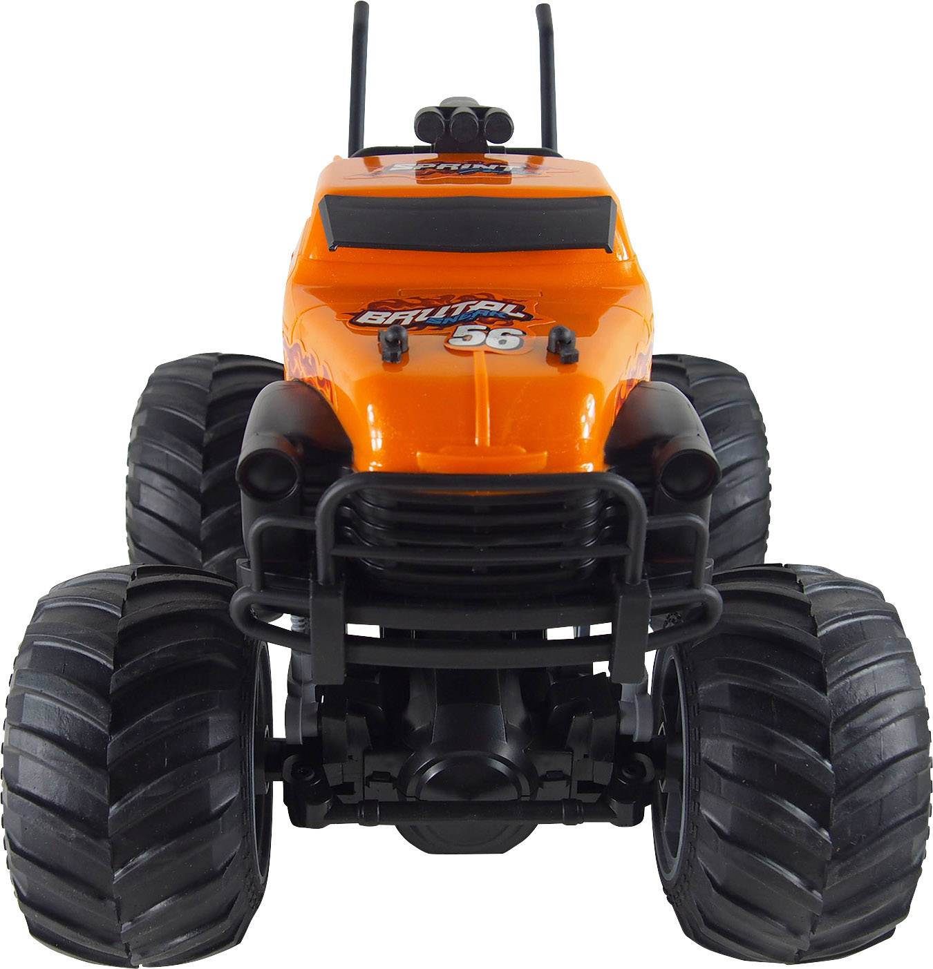 Pomarańczowa zabawkowa ciężarówka monster truck z dużą ramą podwozia i grubymi, czarnymi oponami, ustawiona przodem.