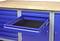 Niebieska szafka warsztatowa z wysuniętą szufladą. Szafka posiada kilka szuflad i drewnianą powierzchnię.