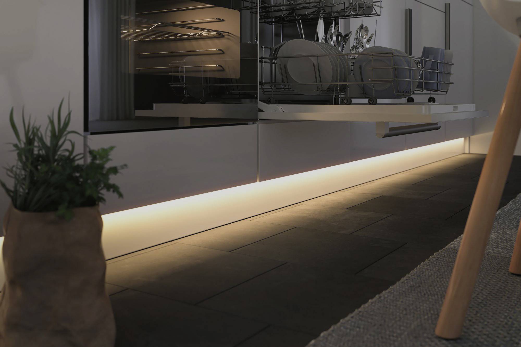 Otwarta zmywarka w nowoczesnej kuchni, naczynia w górnej szufladzie, ciepłe światło bijące od dołu tworzy przytulną atmosferę.
