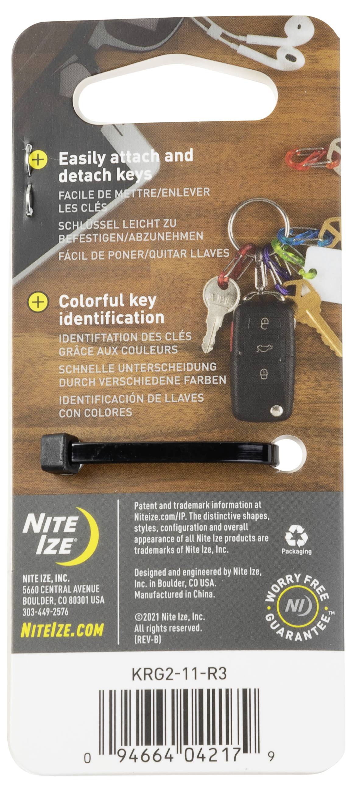 Opakowanie 'Key Clip' prezentujące sposób mocowania kluczy oraz funkcje identyfikacyjne z kodowaniem kolorystycznym. Zawiera cztery klucze z klipsem, umieszczone na drewnianym stole.