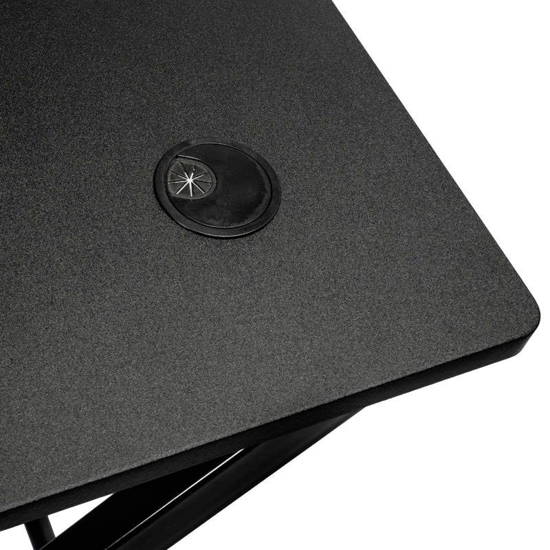 Róg czarnego biurka z przepustem kablowym w lewym górnym rogu.