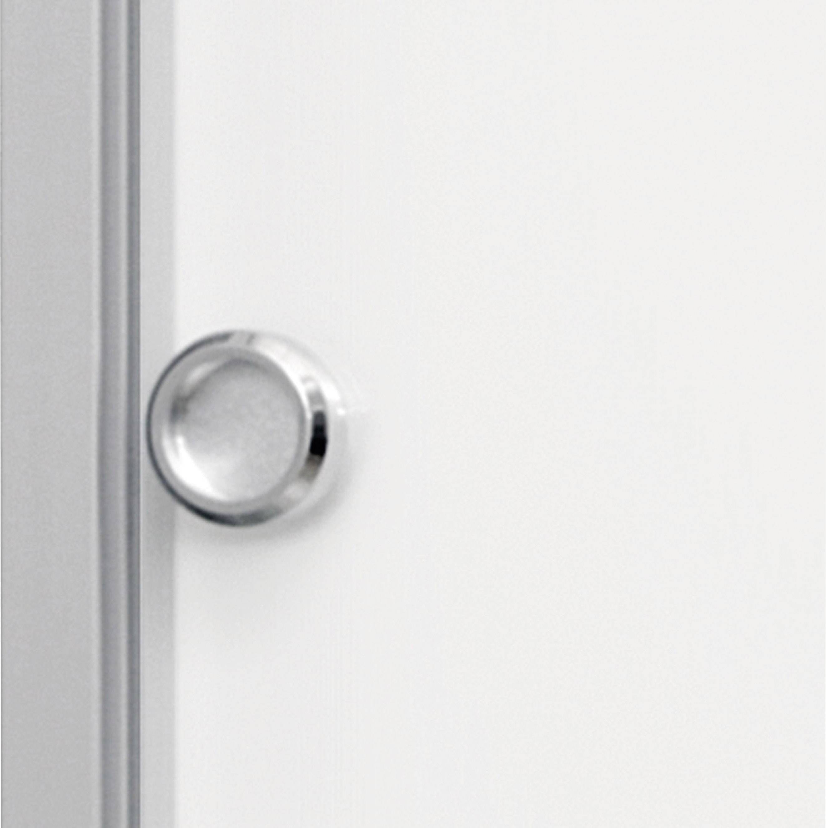 Zbliżenie na okrągłą, srebrną klamkę na białych drzwiach.