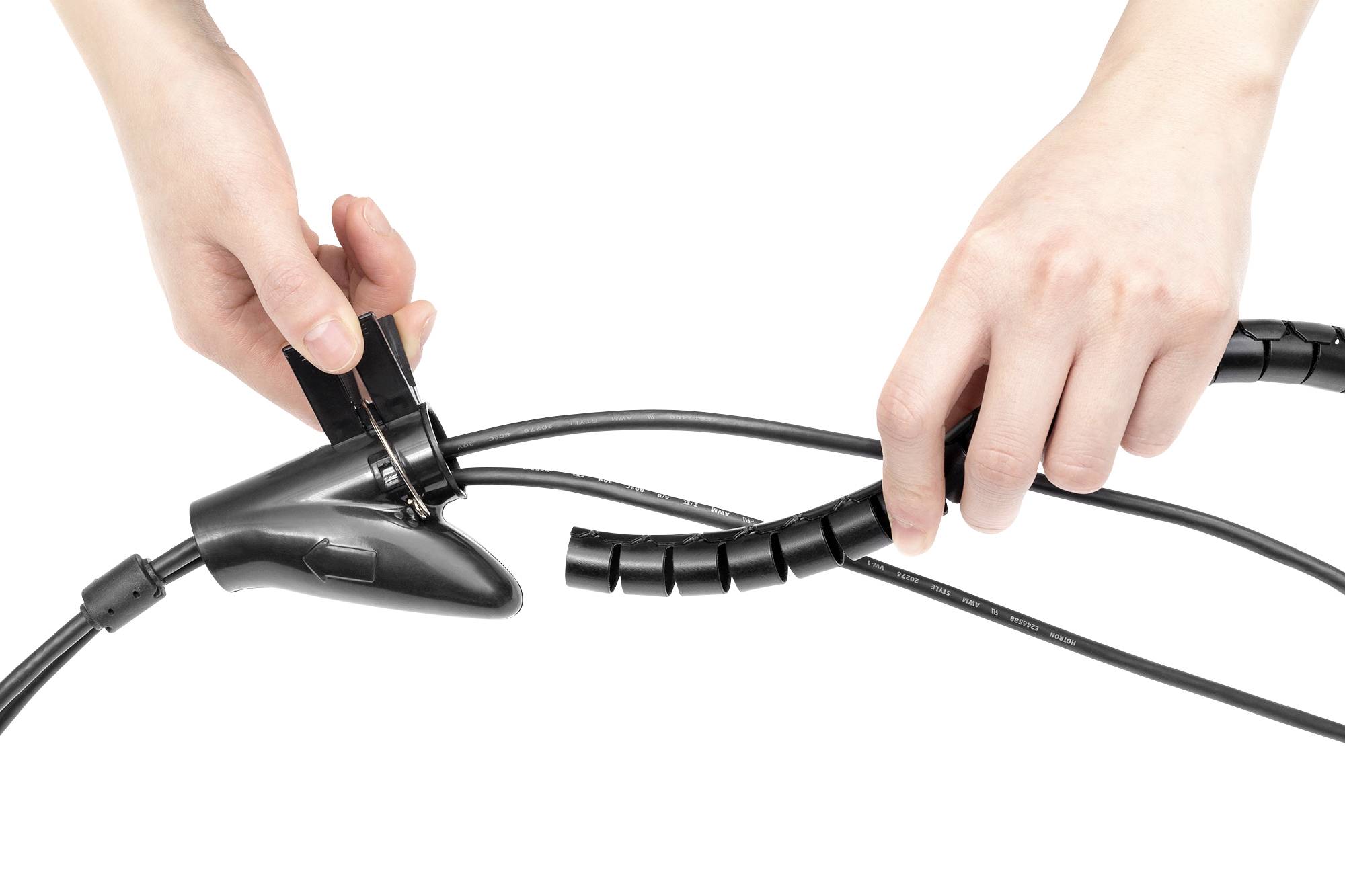 Dwie ręce owijają czarny kabel elastyczną spiralą, aby go związać i uporządkować.