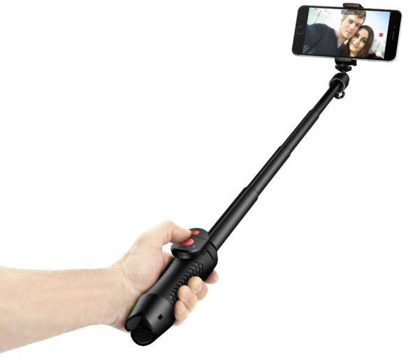Jedna ręka trzyma czarny selfie-stick z podłączonym smartfonem, który rejestruje zdjęcie dwóch osób.