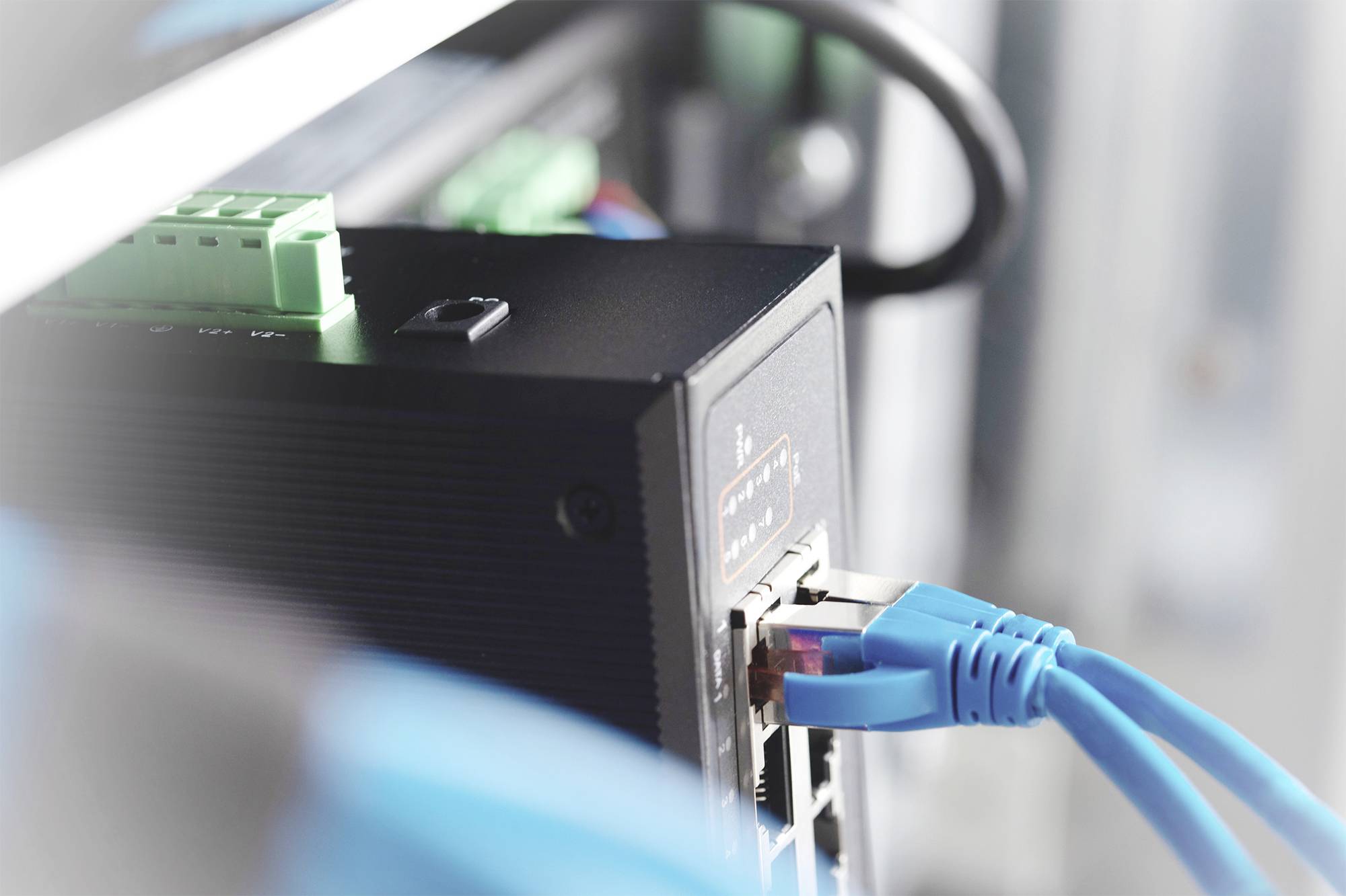 Urządzenie sieciowe z wieloma podłączonymi niebieskimi kablami Ethernet, symbolizujące łączność i transmisję danych w serwerowni.