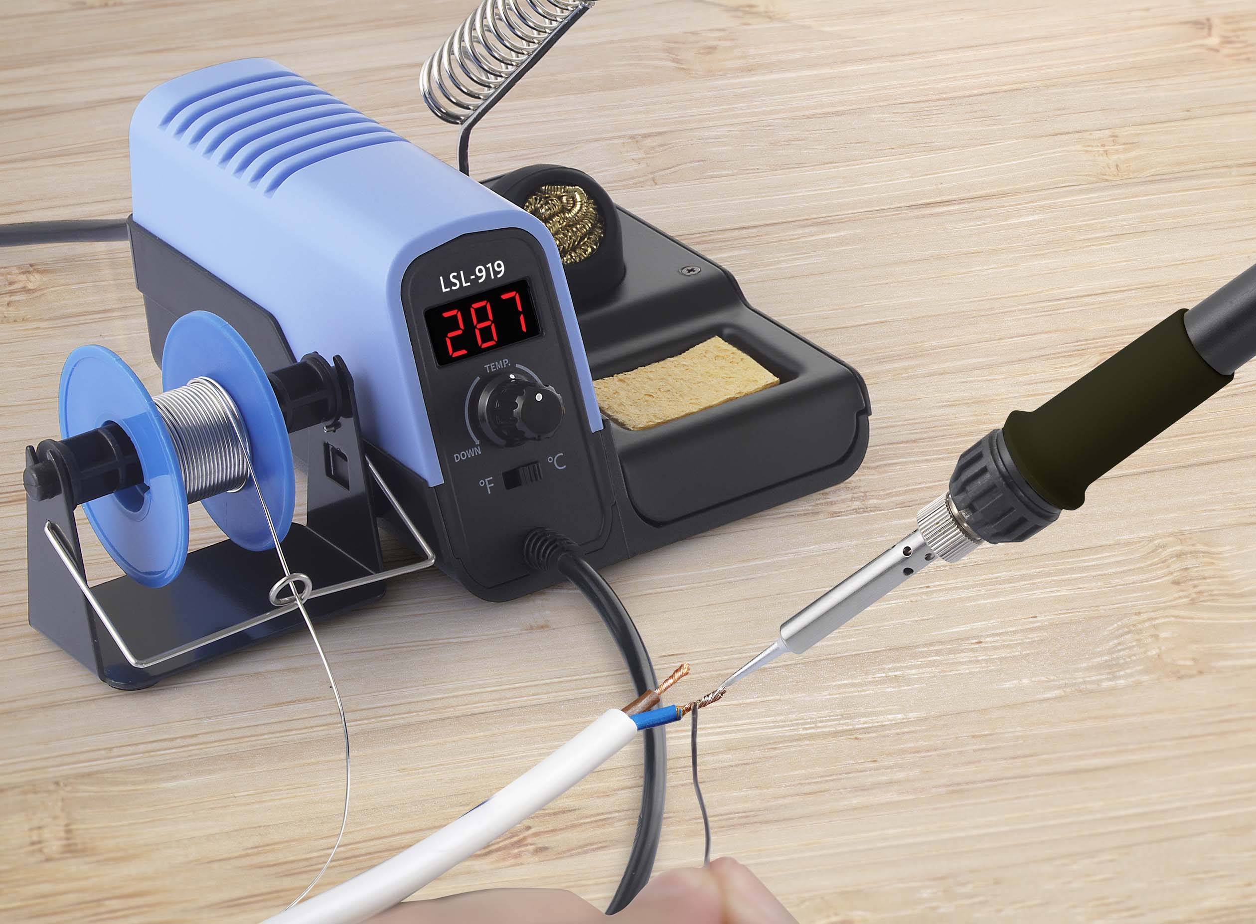 Osoba lutuje przewód lutownicą. Na tle widoczna jest stacja lutownicza z cyfrowym wyświetlaczem temperatury.