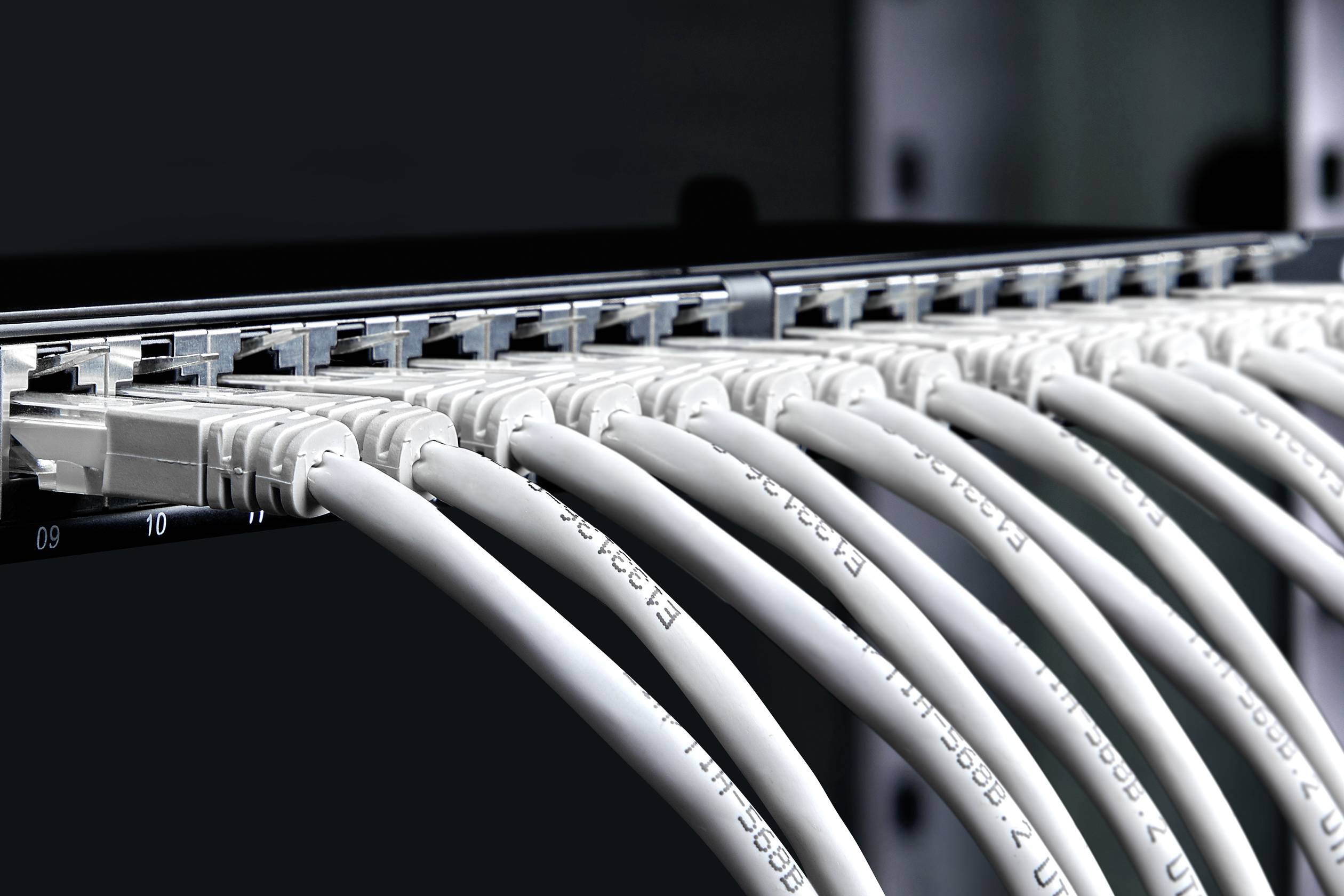 Przełącznik sieciowy z podłączonymi wieloma kablami Ethernet prezentuje infrastrukturę IT w centrum danych.