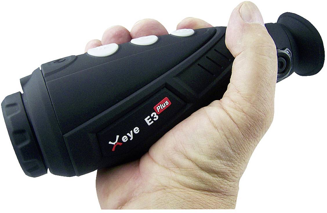 Ręka trzyma urządzenie termowizyjne, model 'Xeye E3 Plus', z kilkoma białymi przyciskami, gotowe do użycia.