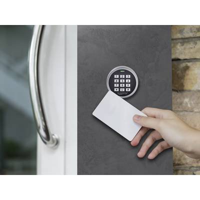 Ręka trzyma białą kartę dostępu przed elektronicznym systemem drzwiowym z klawiaturą do kontroli wejścia.