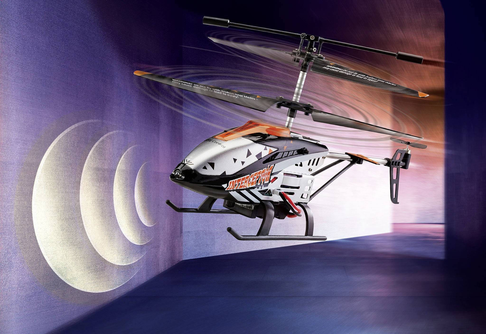 Zdalnie sterowany helikopter z napisem 'Missile Military' lata w niebieskiej przestrzeni. Śmigła są w ruchu.