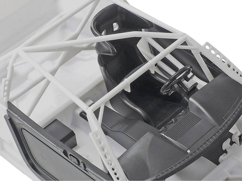 Wnętrze samochodu modelowego z fotelem wyścigowym, klatką bezpieczeństwa i kierownicą wykonaną z czarnego i białego tworzywa sztucznego.