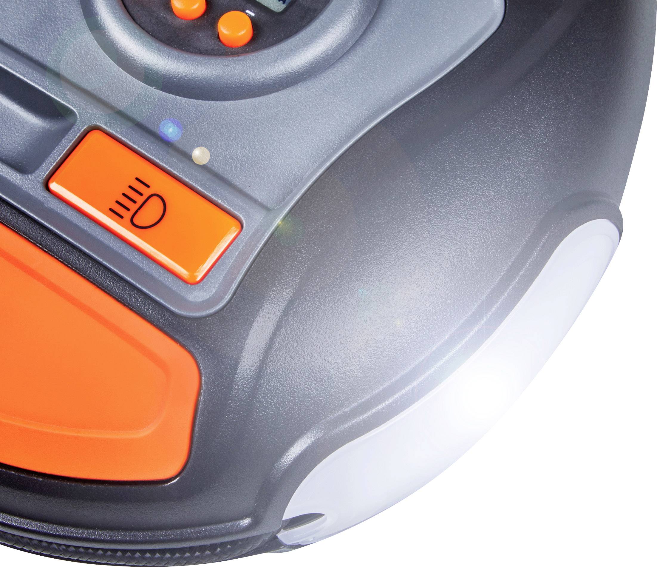 Okrzągłe urządzenie z pomarańczowymi przyciskami i symbolami, prawdopodobnie lampa lub narzędzie. Światło świeci po prawej stronie.