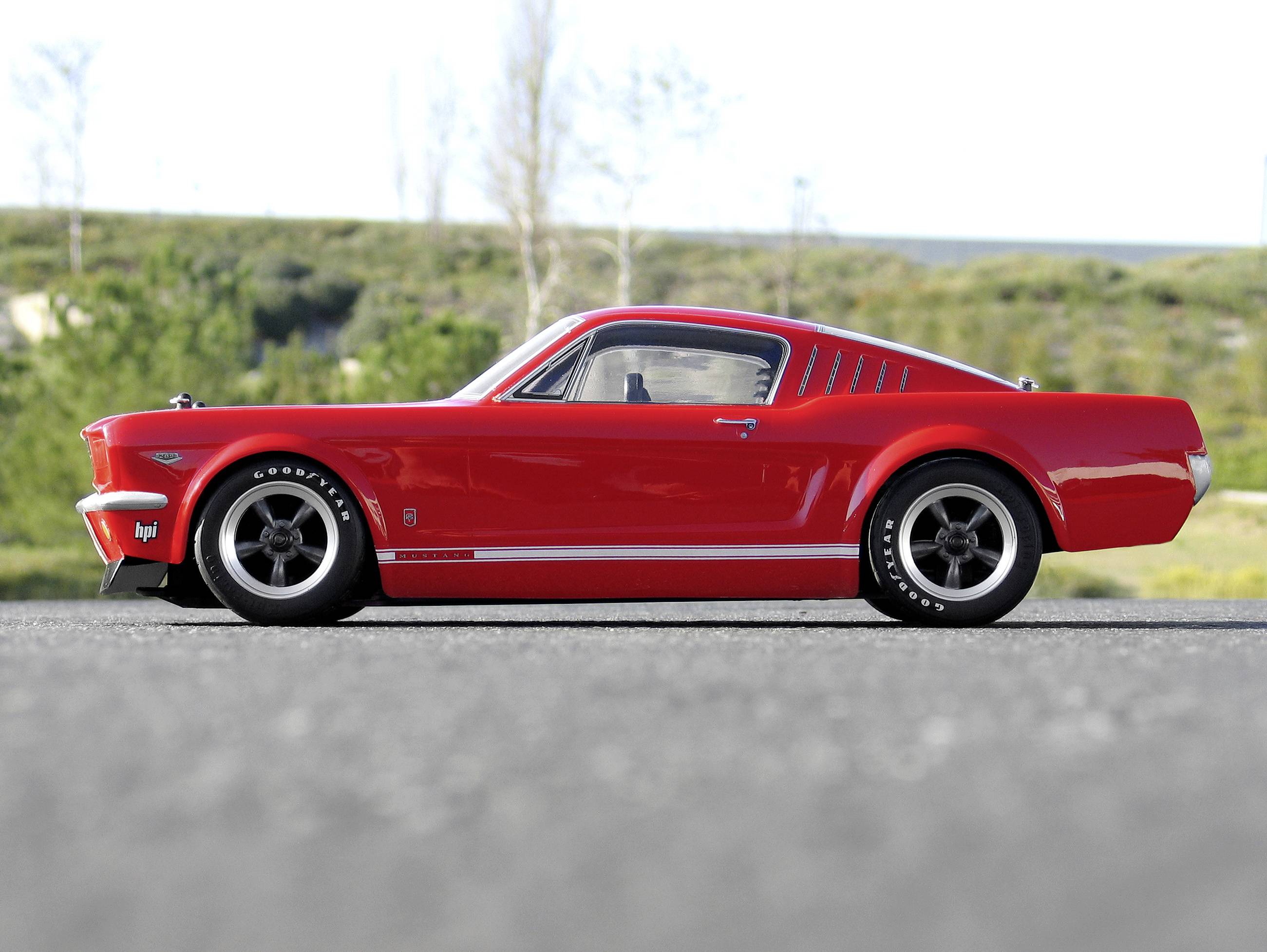 Czerwony model samochodu widziany z profilu na drodze, na rozmytym, zielonym tle.