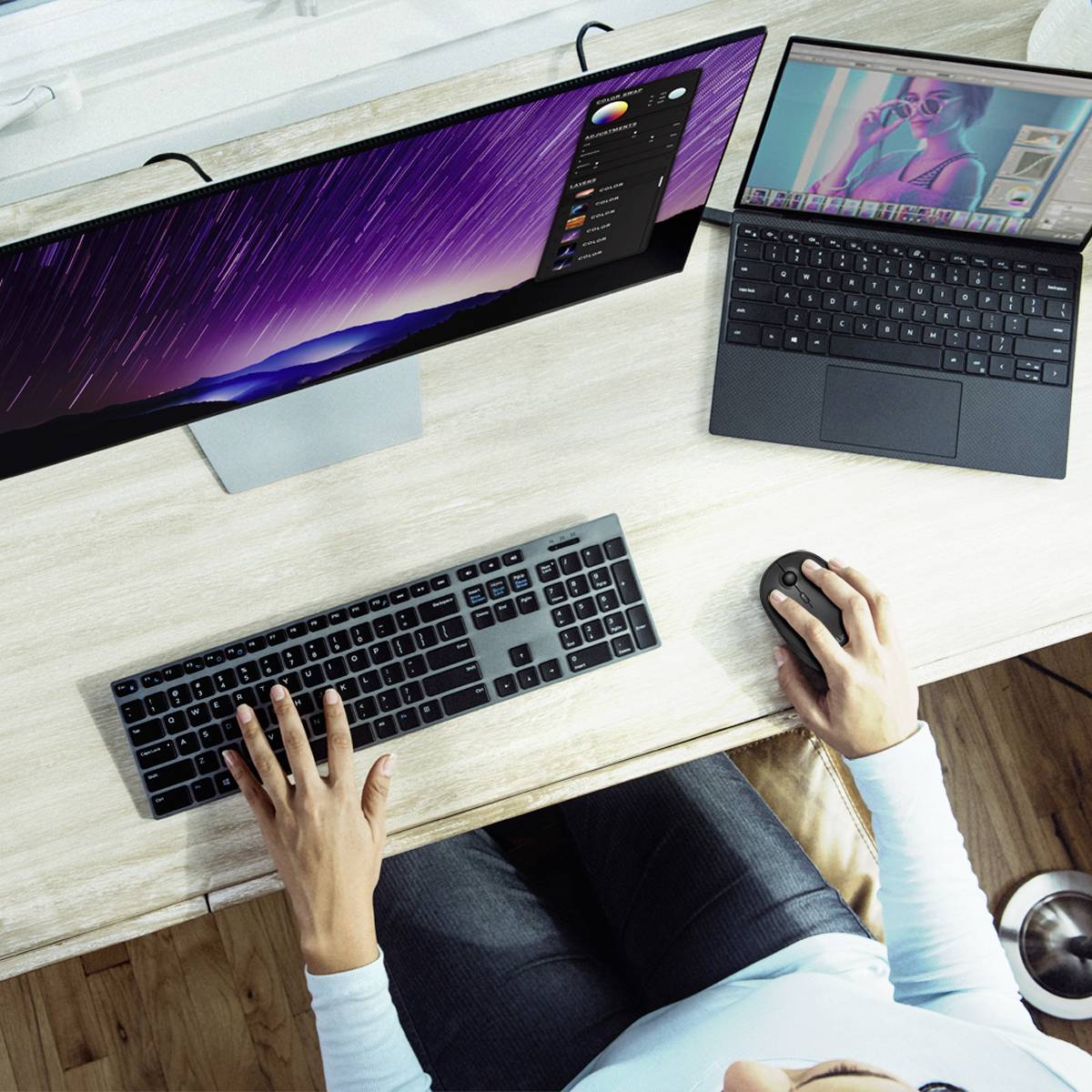 Osoba pracuje przy biurku z dwoma monitorami; jeden wyświetla zdjęcie w oprogramowaniu do edycji grafiki, drugi przeglądarkę internetową.