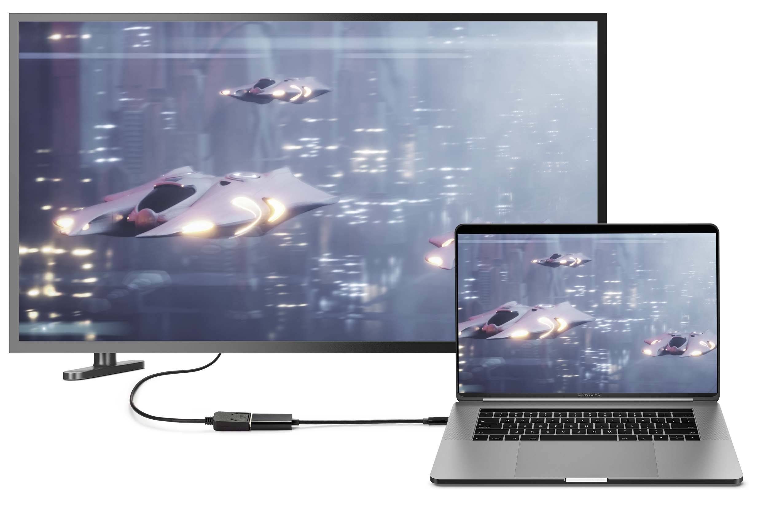 Laptop jest podłączony do monitora, który wyświetla futurystyczną panoramę miasta z latającymi samochodami. Oba ekrany pokazują ten sam obraz.