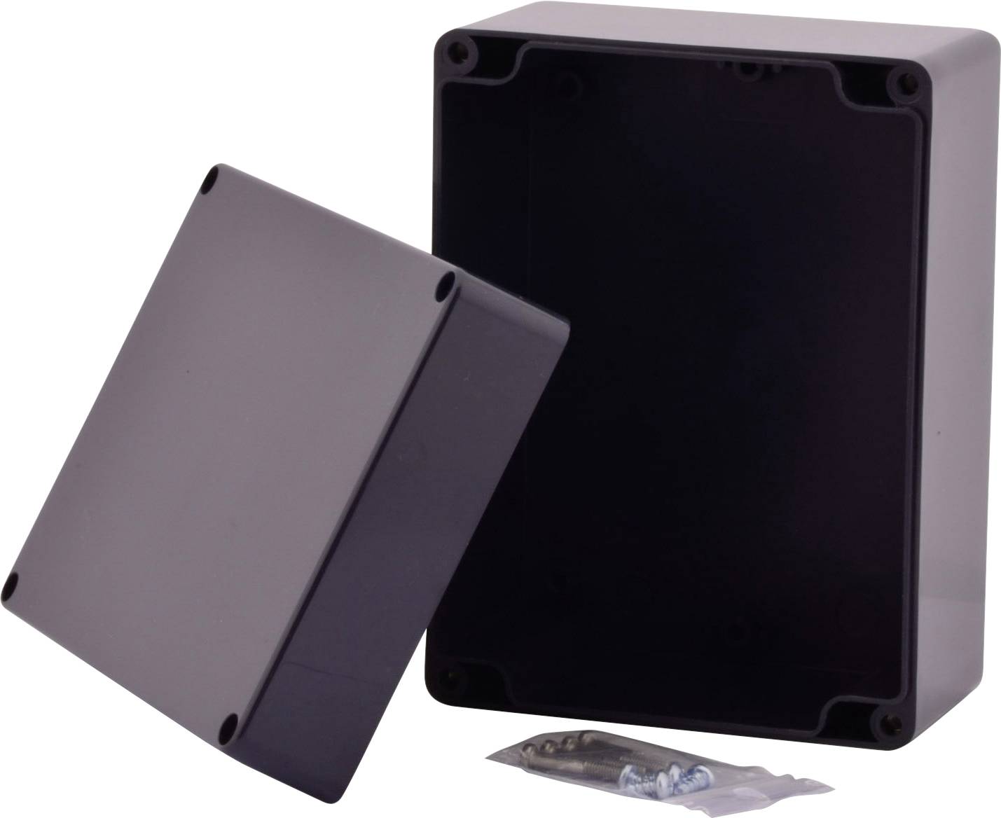 Czarno-szare, prostokątne obudowa z tworzywa sztucznego z odkrytą pokrywą, obok worek ze śrubami. Odpowiednia do projektów elektronicznych.