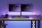 Nowoczesne biurko z dwoma zamontowanymi monitorami, klawiaturą RGB, myszą, uchwytem na smartfona oraz oświetleniem LED.