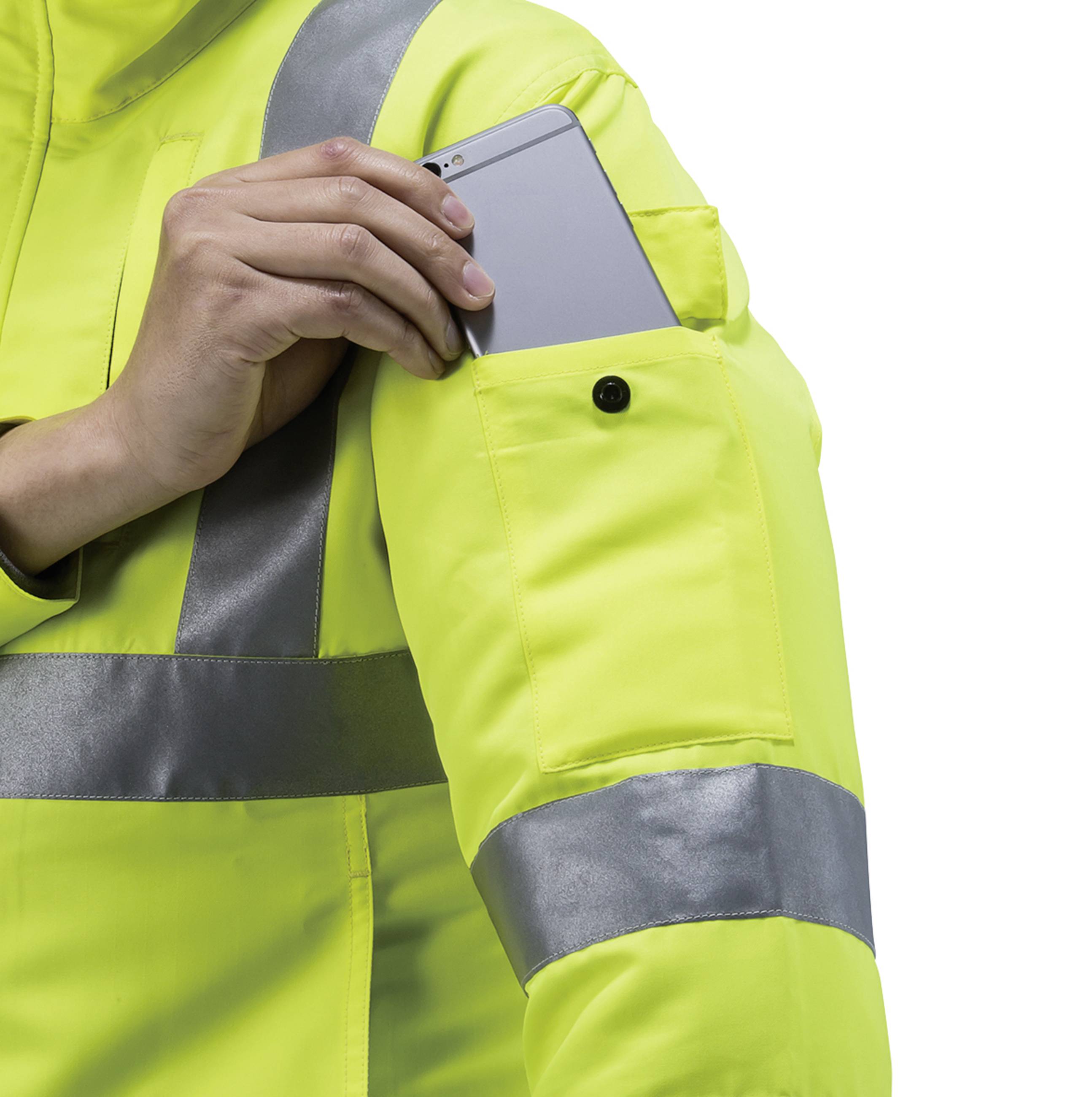 Osoba w żółtej kamizelce odblaskowej wkłada smartfon do kieszeni na rękawie.